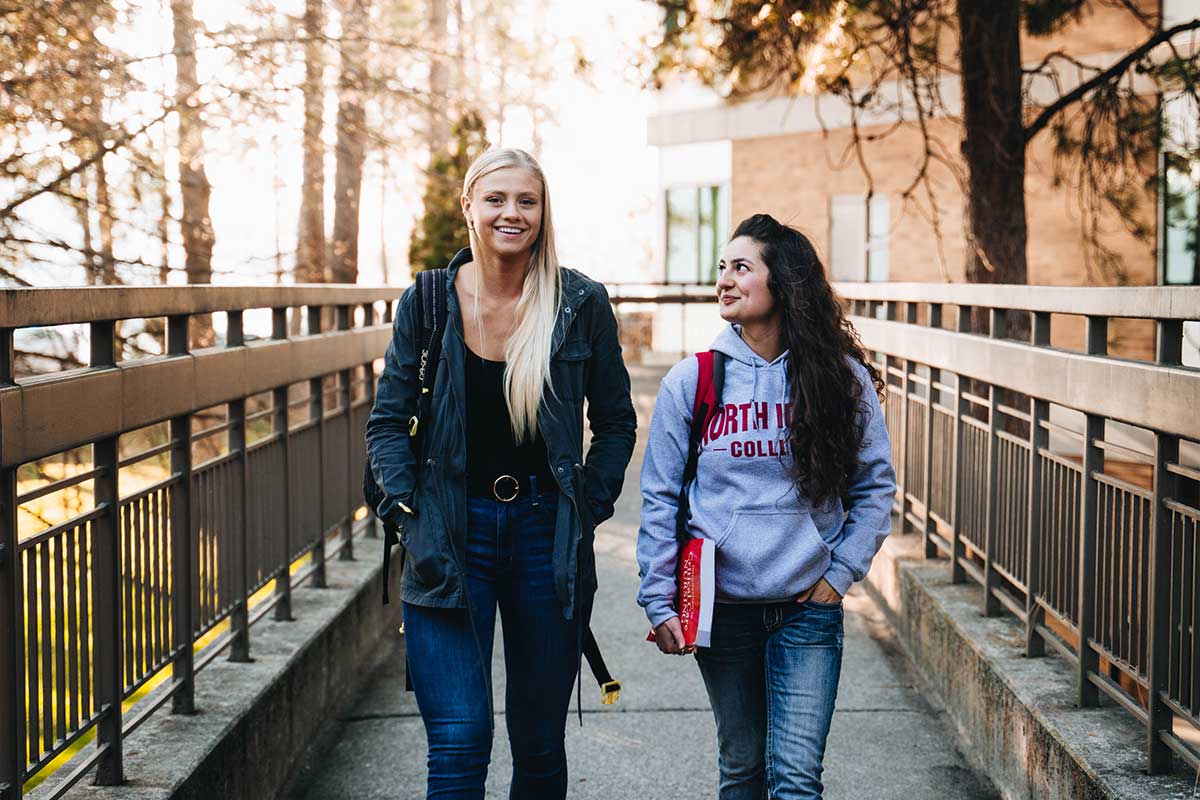 Two female students talking and walking on campus