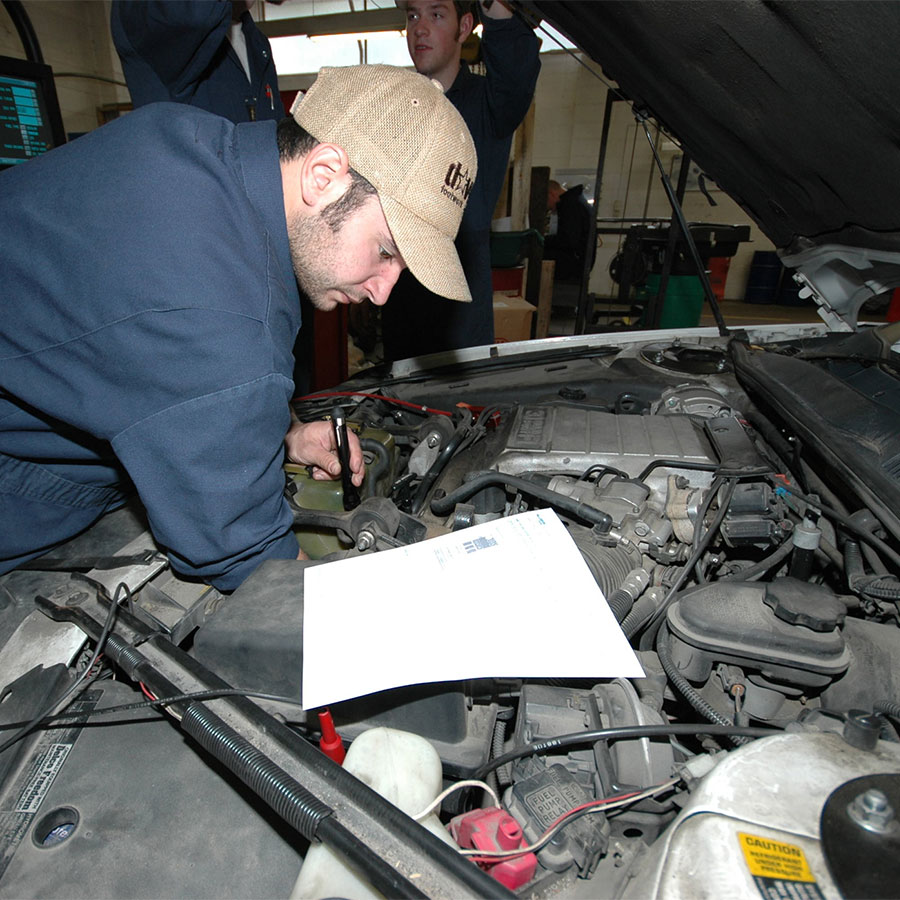 Student working under the hood of a car