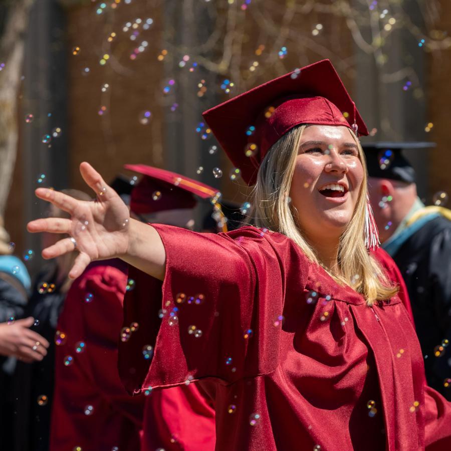 female graduate arms open while bubbles fall around her