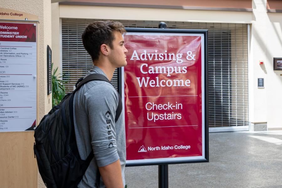 900 x 600 Student walking by Advising Session Event Sign to the event