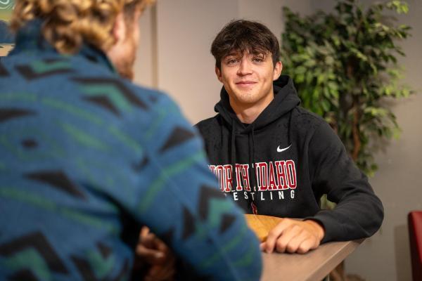 Male Student talking to a person at a table