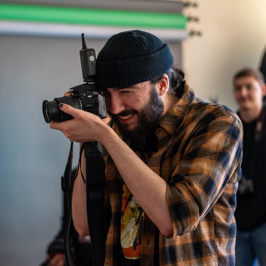 Male student with camera to face at Photography class