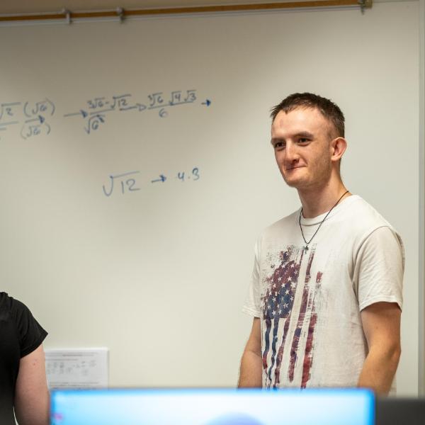 Student doing math problems on whiteboard presenting to class