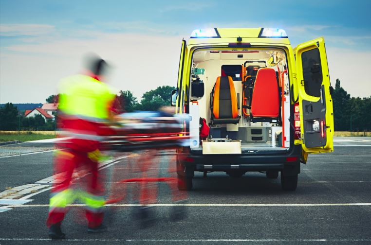 An EMT wheeling a patient to an ambulance