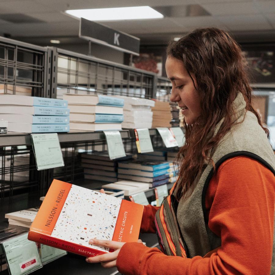 900x900 Female student looking at book from Bookstore