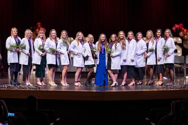 From left, NIC Dental Hygiene graduates Alexis, Alyssa, Kalli, Sonya, Jessie, Lauren, Angelea, Brooke, Reanna, Julissa, Shaylie, Bailey, Kelly, Emily and Bayleigh Stockton celebrate on stage during NIC’s dental hygiene graduation on Dec. 11 at the Boswell Hall Schuler Performing Arts Center at NIC’s Coeur d’Alene campus.