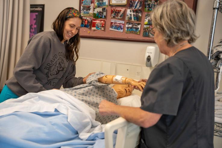 A Certified Nursing Assistant student practices her skills while an NIC Workforce Training Center instructor observes.