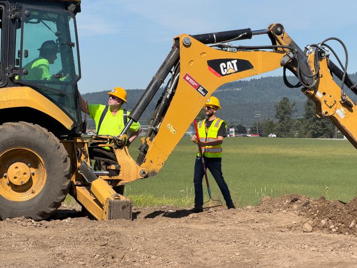A North Idaho College Workforce Training Center heavy equipment operation instructor speaks to a student learning to dig with a backhoe Friday, June 15 at the NIC Parker Technical Education Center in Rathdrum.