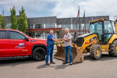 NIC Executive Director of Workforce and Economic Development Colby Mattila, left, receives the keys to a 2020 Caterpillar 420E loader backhoe from ACI Northwest, Inc. President and CEO Bill Radobenko on Wednesday, July 22 and the NIC Parker Technical Education Center in Rathdrum.