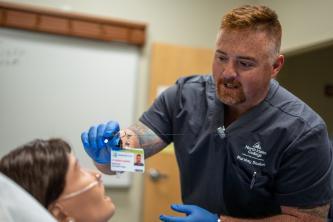 Male Nursing Student doing clinicals on a maniquin